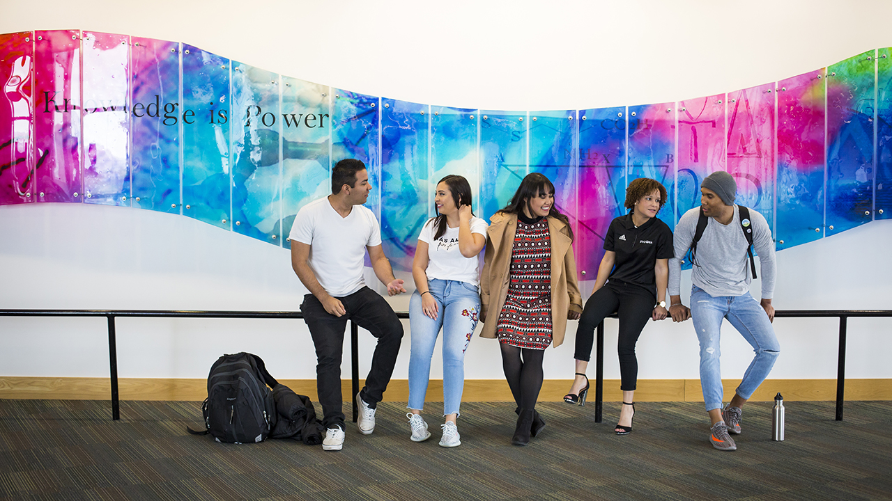 A group of students standing in front of a colorful mural